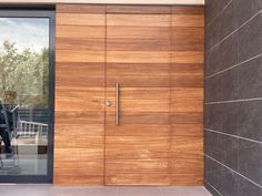 a large wooden door in front of a brick wall with glass doors on both sides