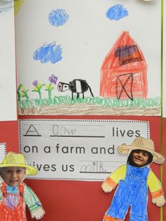 two children's paper dolls are standing in front of a bulletin board with farm animals on it