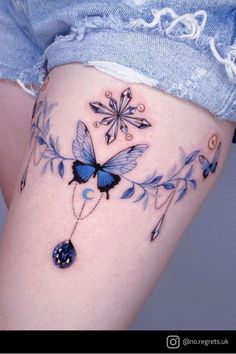 a woman's thigh with blue butterflies and flowers on the bottom part of her leg