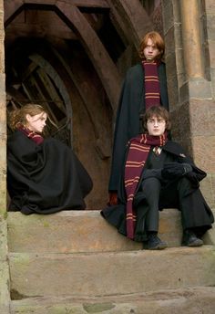 three people dressed in harry potter costumes sitting on steps