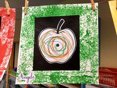 an apple is hanging on a clothes line with other art supplies in front of it