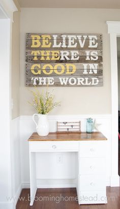 a wooden sign that says believe there is good in the world above a white desk