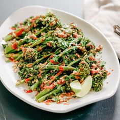 a white plate topped with broccoli covered in seasoning next to a bowl of rice