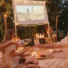 a group of people sitting on top of a blanket next to each other eating cake