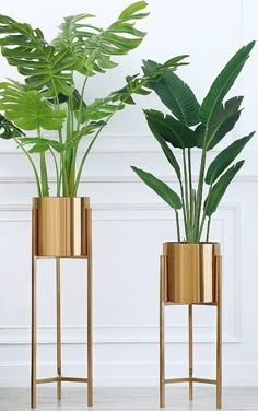 two gold planters with plants in them sitting on the floor next to each other