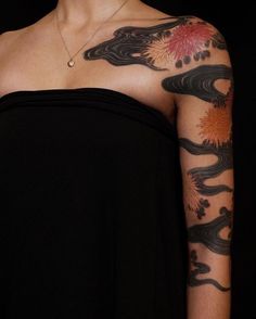 a woman's arm with tattoos on it and flowers painted on the back of her arm