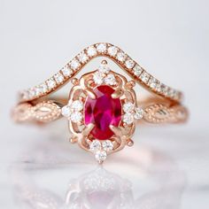 a close up view of a ring with a red stone in the center and white diamonds surrounding it