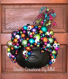 a black pot filled with lots of colorful christmas ornaments on top of a wooden door