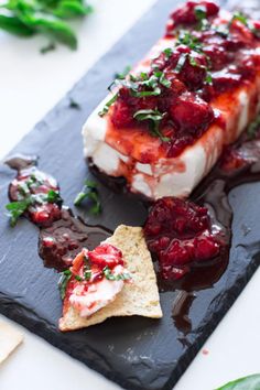 a piece of food that is sitting on a black plate next to some crackers