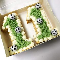 a cake shaped like the letter e with soccer balls on it in a cardboard box