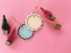 three small christmas tree ornaments on pink background