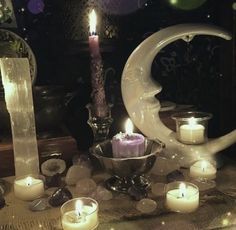 a table topped with lots of candles next to a moon and crescent shaped candle holder