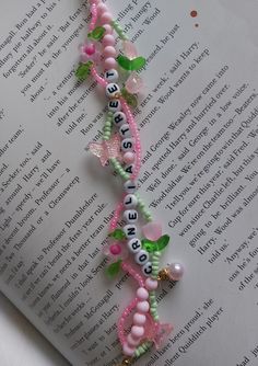 the book is laying on top of the page with beads and butterflies attached to it