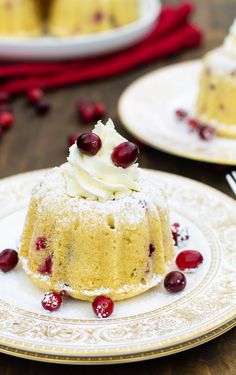 two small cakes with white frosting and cranberries on plates