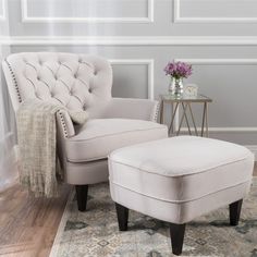 a chair and ottoman in a living room with a floral arrangement on the side table