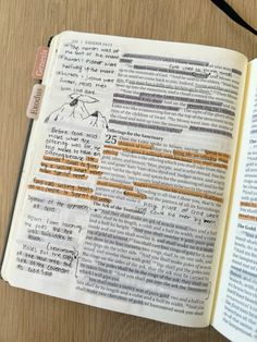 an open book with writing on it sitting on top of a wooden table next to a cell phone