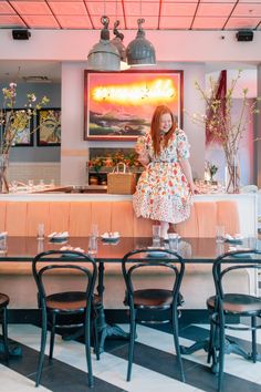 a woman in a pink dress standing at a table