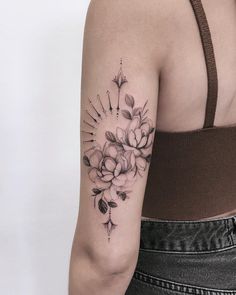 a woman's arm with flowers and arrows tattooed on the left side of her arm