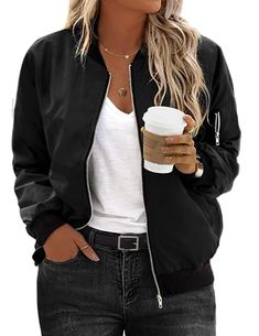 a blonde woman wearing sunglasses and a black jacket holding a cup of coffee in her hand