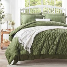 a bed with green comforter and white pillows