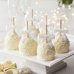 white chocolate covered apples on a platter next to some wine glasses and champagne flutes