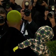 a man in a clown suit is surrounded by photographers