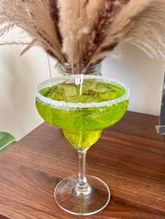 a green drink in a wine glass on a table