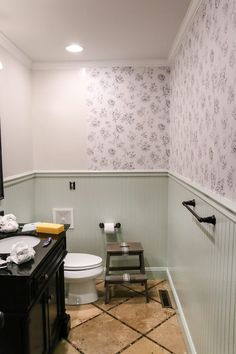 a bathroom with floral wallpaper and tile flooring, along with a black vanity