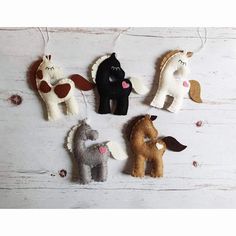 four felt animals hanging from strings on a white wooden surface