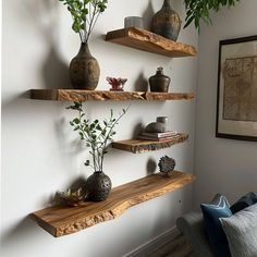 three wooden shelves with plants and vases on them in a living room area,