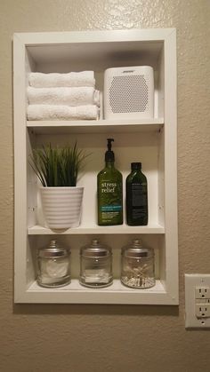 a bathroom shelf filled with white towels and other items