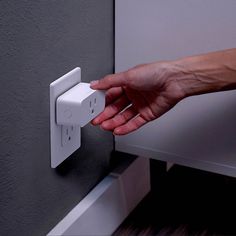 a person's hand is pressing the light switch button on a wall mounted outlet