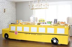 a yellow school bus shaped buffet table in a living room with white brick walls and wooden floors