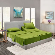 a bed with green sheets and pillows in a room