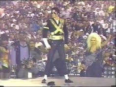 a man in uniform standing on top of a stage next to a blonde haired woman