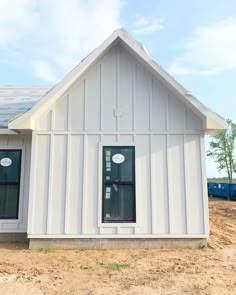 a small white house with solar panels on it's roof and windows in the front