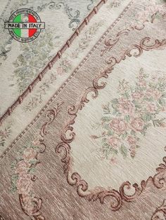 an antique rug with pink flowers and scrolls on the bottom, in front of a white background