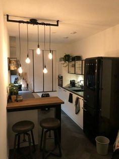 a black refrigerator freezer sitting inside of a kitchen next to a counter with stools