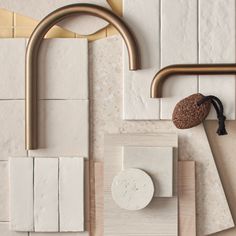 an assortment of white and brown tiles with brass fixtures on the wall next to each other