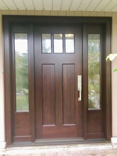 a wooden door with two sidelights and glass panels on the front of a house