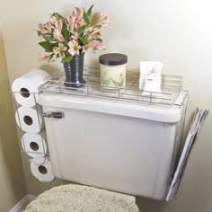 a white toilet sitting in a bathroom next to a vase with flowers on top of it