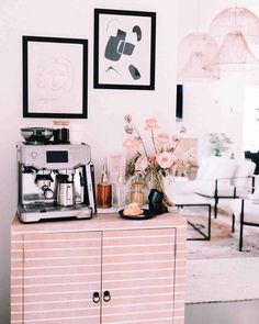 a coffee machine sitting on top of a pink cabinet next to a vase with flowers