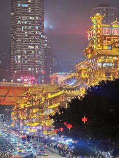 a city street filled with lots of traffic and tall buildings in the background at night