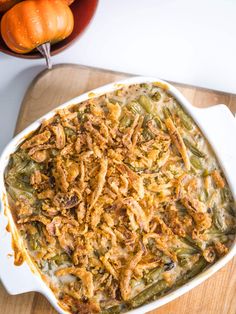 a casserole dish filled with green beans and other vegetables on a cutting board