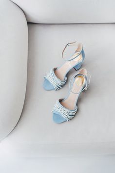 two pairs of blue high heeled shoes sitting on a white couch next to each other