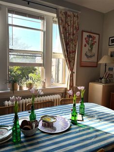 the table is set for two with plates and flowers in vases on top of it