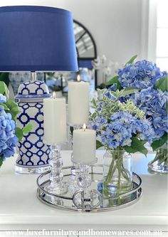 blue and white vases with flowers in them on a table next to a lamp