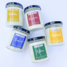 four jars of candles sitting next to each other