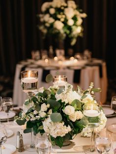 the centerpieces on this table are filled with white flowers and greenery