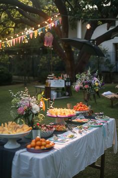 a table full of food sitting on top of a lush green field next to a tree